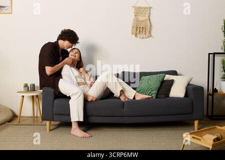 A curly-haired man leans in to playfully tease his beautiful partner as they relax together. Stock Photo