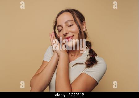 Woman with closed eyes and hands together, looking peaceful. Stock Photo