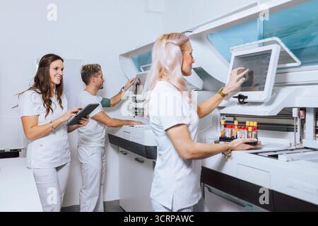 Medical professionals in a lab process samples using advanced equipment while collaborating on tasks and managing data. Stock Photo