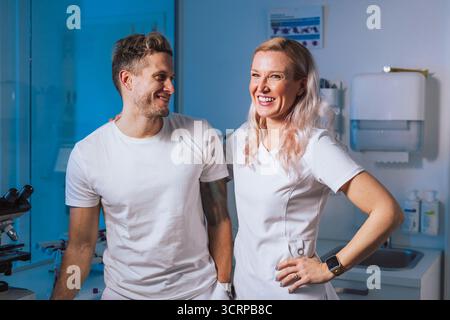 Two healthcare professionals share a joyful moment in a bright, modern clinic during their working hours. Stock Photo