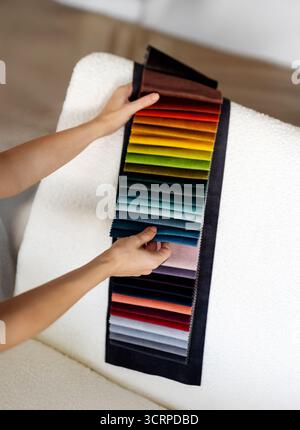 Woman's hands examine samples of bright colored velvet fabrics. Interior design, consulting, and home renovation. Choosing upholstery materials for re Stock Photo