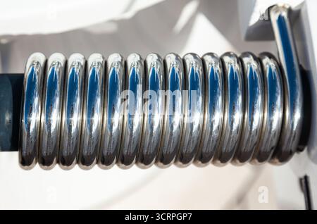 Stainless steel spring on the door hinge for quick closing, close-up. Stock Photo