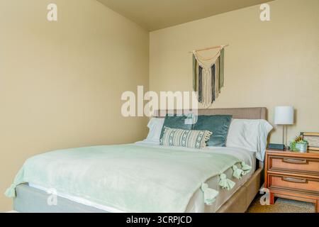 Bedroom blue green pillows, bed, nightstand, macrame wall art, desert southwest theme Stock Photo
