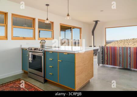Modern desert home kitchen with stainless steel stove and oven. Open floor plan living room with large windows Stock Photo