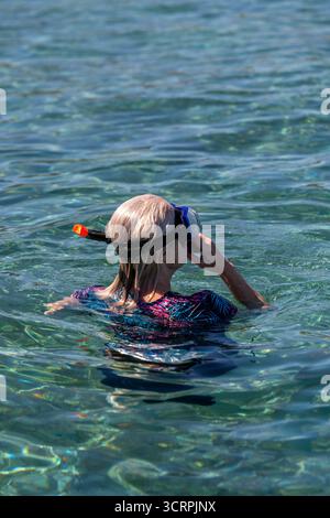 young woman wearing a diving mask and snorkel swimming in the crystal-clear turquois mediterranean waters on the Greek island of Zante or Zakynthos Stock Photo