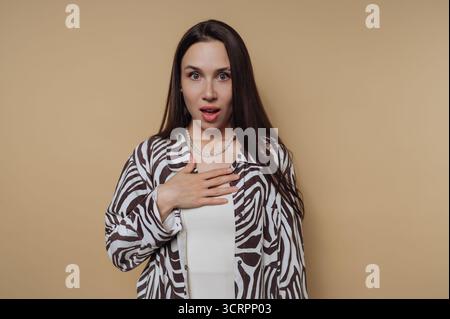Woman with surprised expression against beige background Stock Photo