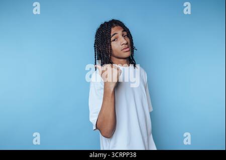 Young man with dreadlocks in white t-shirt against blue background Stock Photo