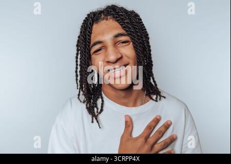 Smiling young man with dreadlocks and braces, wearing a white shirt. Stock Photo
