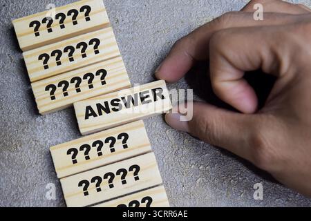 Question mark icon and selected answer on stacked wooden cubes on the table. Business and finance concept Stock Photo