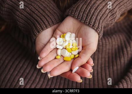 Hands of young woman holding different vitamins and pills. Concept of supplement use, healthcare and prevention during illness or seasonal weakness. Stock Photo