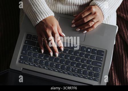 Woman working remotely from bed using laptop. Home office comfort during illness or lazy morning. Freelance work concept and cozy productivity at home Stock Photo