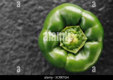 Green bell pepper closeup on dark background. Fresh vegetable macro photo showing natural texture. Healthy eating and organic food concept. Stock Photo