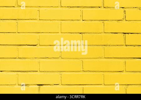 Yellow brick wall texture background. Bright painted masonry surface with geometric construction pattern and urban architectural detail. Stock Photo