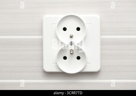 White electric power socket on wall. Modern household interior detail with safe plug connection. Home electricity and energy supply concept. Stock Photo