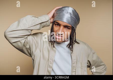 Young man with a confused expression wearing a durag and casual shirt. Stock Photo