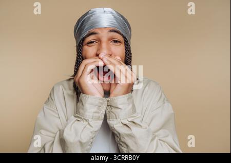 Young man with a durag shouting with hands around mouth. Stock Photo
