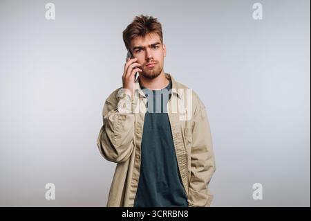 Young man with a serious expression talking on a smartphone. Stock Photo