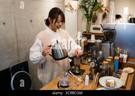 TOKYO, JAPAN - 28 OCTOBER, 2024 - Horizontal picture of a japanese woman preparing coffee at a coffee shop located in Tokyo Stock Photo