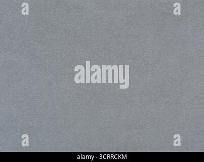 Grey surface of an old paper or cardboard, background, texture. Backdrop of gray paper surface with elements of aging. Old and shabby paper piece Stock Photo