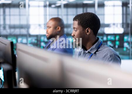 Team of technicians in data center workspace running system diagnostic tests and error checking utilities to fix problems. Coworkers looking for network issues affecting rigs performance Stock Photo