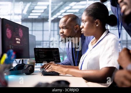 Team of programmers in server hub doing brainstorming, working to protect equipment from hacker. IT staff members facility in data center struggling to fix security breach alert Stock Photo