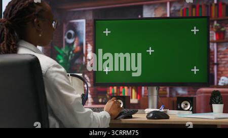 Student at home browsing internet on green screen computer, doing homework, researching information online. Girl in apartment reading articles on mockup PC for school tasks, camera B Stock Photo
