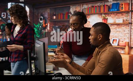 Teamworking programmers creating deep learning models analyzing data in artificial intelligence development agency. African american IT coworkers programming in AI startup office, camera A Stock Photo