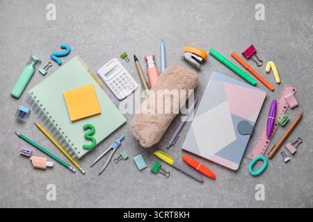 Composition with notebooks and different school stationery on grey grunge background Stock Photo