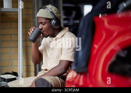 Young Adult Black Man Listening to Music and Drinking Coffee Indoors Stock Photo