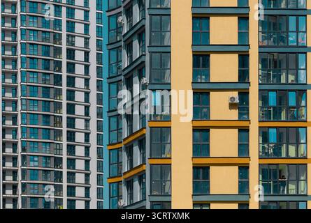 Closeup of modern multistorey residential building facade. Glass windows and balconies create geometric pattern on tall tower. Urban architecture, hou Stock Photo