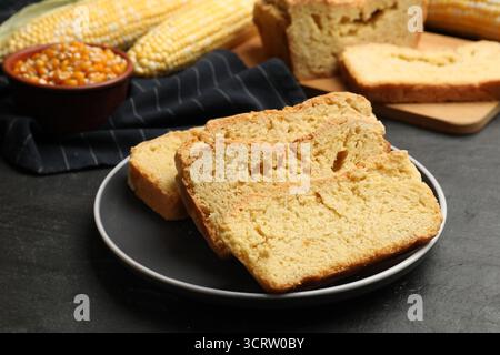 Freshly baked cornbread, cobs and seeds on black table, closeup Stock Photo