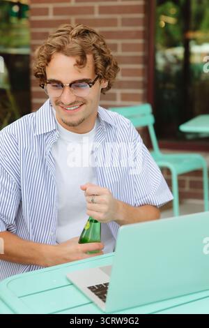 Young man smiling working on laptop relaxing outdoors Stock Photo
