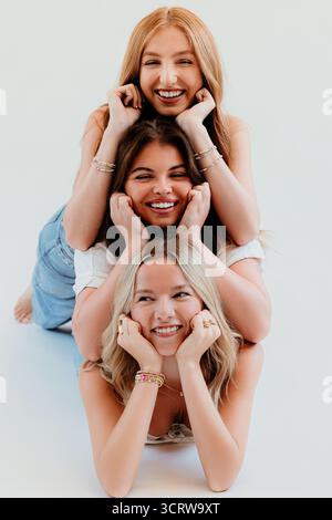 Three friends in stacked pose laughing and smiling warmly Stock Photo