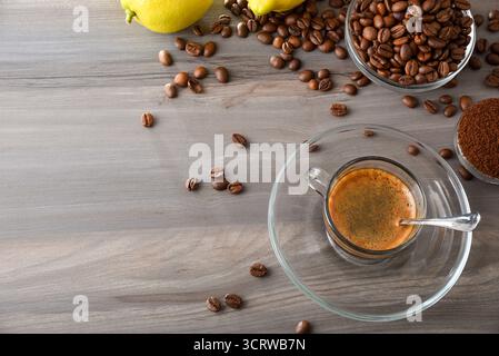 Glass cup of traditional coffee on a plate on a wooden table with containers of coffee beans, ground coffee, and lemons. Top view. Stock Photo