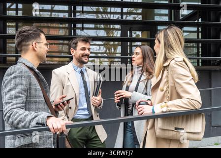 IT experts freelance workers innovative technology developers, working on a new project staff meeting with casual talk in formalwear outside office bu Stock Photo