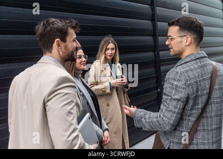 IT experts freelance workers innovative technology developers, working on a new project staff meeting with casual talk in formalwear outside office bu Stock Photo