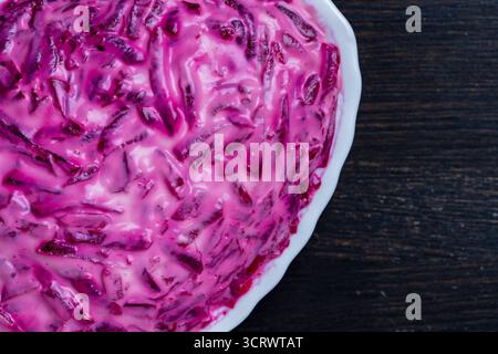 Traditional Ukrainian salad in a plate called Herring under a fur coat or shuba on wooden table, close up, top view Stock Photo