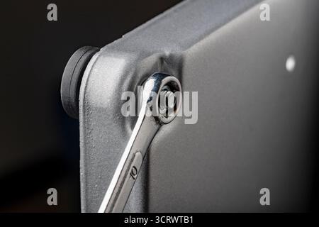 We tighten the nut on the bolt thread in the steel workpiece with a wrench. Metal spanner, bolt, screw and nuts, close up Stock Photo
