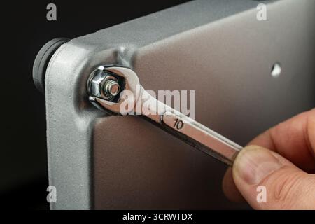 We tighten the nut on the bolt thread in the steel workpiece with a wrench. Metal spanner, bolt, screw and nuts, close up Stock Photo