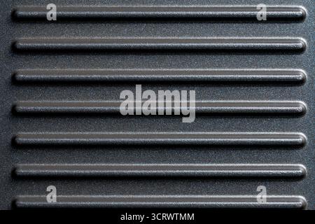 Black grill non-stick die-cast aluminum plates for design purpose, close up, top view. Electric grill plate as background or texture. ribbed striped g Stock Photo