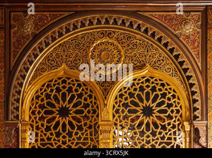 Golden archway featuring geometric lattice panels, ornate arabesque motifs, and carved wood detail. A luxurious example of Islamic architectural artis Stock Photo