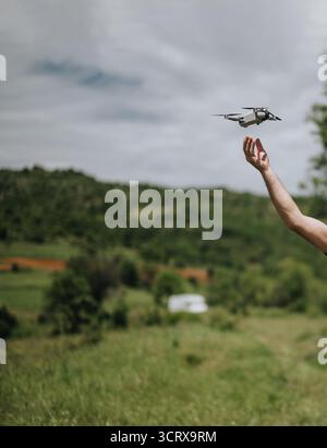 Man operating a drone in a scenic green outdoors landscape Stock Photo