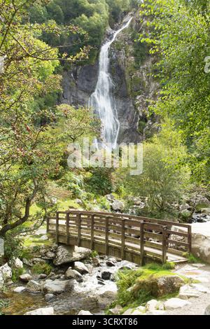 footbridge over the river at Aber Falls, Rhaeadr Fawr, showing the waterfall in September with trees in leaf, Snowdonia, Wales Stock Photo
