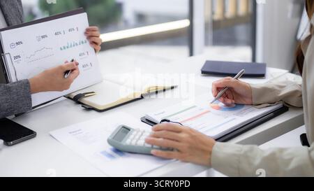 Colleagues discussing business reports performance analyzing data calculations strategic planning workspace documents team cooperation professional en Stock Photo