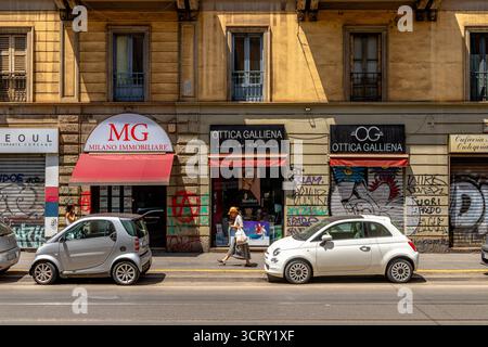A woman walking past the shops and parked cars on Corso Cristoforo  a busy street in Milan,Italy Stock Photo