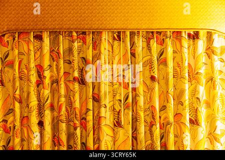 Curtains with floral patterns hanging in a room with soft light, close-up. Stock Photo