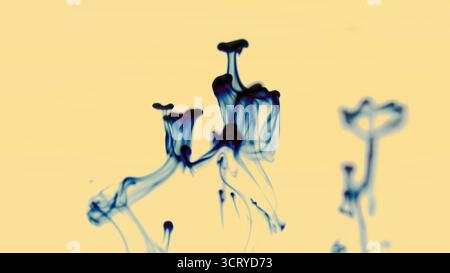Abstract blue ink swirling in water on a soft yellow background creating artistic fluid shapes and smoke-like patterns Stock Photo
