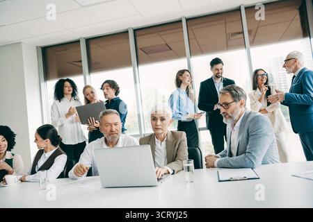 Collaborative office environment showcasing teamwork among diverse professionals communicating and collaborating Stock Photo