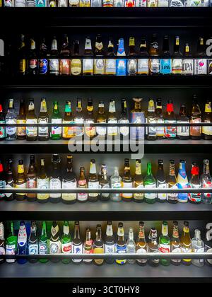 A variety of beer bottles displayed on shelves in a liquor store featuring diverse labels and colorful packaging under bright lighting ipoh malaysia Stock Photo