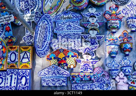A collection of blue and white ceramic items with the word Puebla written on them. The items are arranged on a table and include plates, cups. City of Stock Photo